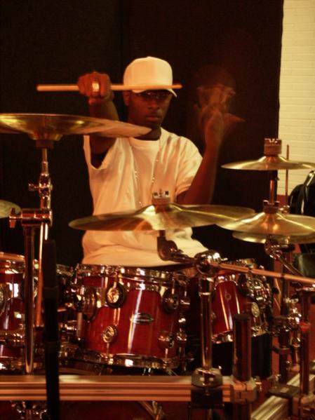 Uriel Carney - Drums


Uriel Carney was born and raised in Kentucky. “ Rhythm Child” as he is fondly called has been playing jazz and gospel drums since his childhood. Starting at the age of 10, his ideal drums were pots, pans and the arm of his grandparents’ love seat.  During his first years in school he was forced to play the clarinet while being told by his band teacher that he was too small to be a drummer.

Being determined, Uriel taught himself to play drums.  He attended church and loved to listen to gospel music.  Before long, he started playing drums at his church.  While attending high school, Uriel went from a freshman 3rd string bass to 1st string section leader snare by sophomore year.  Uriel became the first percussionist at Butler Traditional High to bring a 5-piece drum set to the football games, basketball games, and competition music criteria. His learning to read music scores and charts was just an additive that pushed his ambition.  
In 1990, Uriel was selected as the lead drummer in the national play “Mama I Want To Sing”.   While in high school, Uriel received many awards including Most Talented in Class of 1993, MVP 1992, MVP 1993, Most Distinguished Award from Kentucky State University, where he graduated with music honors.  While attending Jefferson Community College, he began attending drum clinics and opening his music horizons to different styles of music such as rhythm & blues, fusion, Latin American, rock, country and studio drumming.  His influences were Dennis Chambers, Dave Weckl, Billy Cobham, Horacio Hernadez, Zoro and many more.

In 1995, Uriel began teaching drum techniques to young individuals.   At his home church it is here that he earned the name “Rhythm Child” due to his passion for music.  Over the course of his music career, he has been honored to sit in as guest drummer for artists and venues such as Kirk Franklin, Tanita Gaines, Ben Tankard, Donnie McClurkin, Playa, Goodfella, Def Comedy Poetry, Warner Bros.’ live comedy show, Spike Davis’s comedy events and gospel music workshops.
While playing the club scene, Uriel “Rhythm Child” has performed live and on recordings with Paul Bennett and the Second Chance band, BG, Nappy Roots, Kirk Wahlum, Klientel, Adrianne Archie, the battle of the bands 2005, Big Diggity, Code Red, Latin American artist Gracelia, BDP Productions, Buckwheat Jones, Skysirewest Soundchaser, Sleepy Stone and other artists.

Besides his busy playing career, he is an instructor at the River City Drum Corp and is very involved with teaching the aspect of rhythm and the music business, conducting seminars and classes in different cities throughout the United States.  He says, “It is my goal to inspire people young and old, contributing a positive action towards spiritual growth and happiness.”